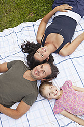 Eine glückliche bayerische Familie, die sich auf einer Picknickdecke in der Sonne sonnt und pure Freude ausstrahlt - SKF000602