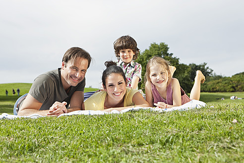 Eine glückliche bayerische Familie genießt einen sonnigen Tag, liegt auf einer Picknickdecke und lächelt für ein Foto - SKF000608