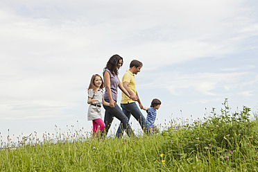 Eine bayerische Familie genießt einen gemütlichen Spaziergang in einem grünen deutschen Park, umgeben von üppigem Laub - SKF000617