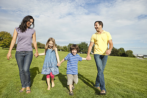 Germany, Bavaria, Family walking in grass at park - SKF000622