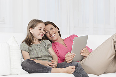 A happy mother and daughter in Munich, Germany, bonding over a digital tablet and sharing a smile - SKF000650