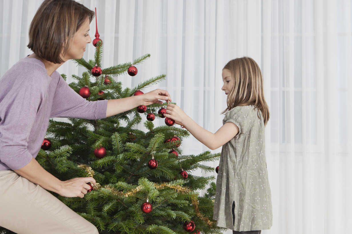 Mom and daughter decorate the Christmas tree Stock Photo by