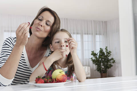 Eine glückliche Mutter und ihre Tochter genießen frisches Obst in München, Deutschland, lizenzfreies Stockfoto