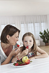 Eine glückliche Mutter und ihre Tochter genießen einen gesunden Snack aus frischen Früchten in München, Deutschland - SKF000654