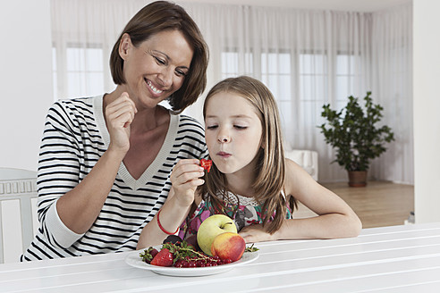Eine glückliche Mutter und ihre Tochter genießen einen gesunden Snack aus frischen Früchten in München, Deutschland - SKF000655