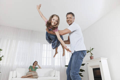 Deutschland, München, Vater spielt mit Tochter, Mutter im Hintergrund, lizenzfreies Stockfoto