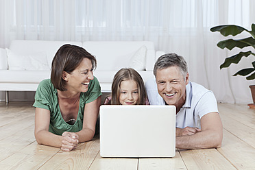 Eine glückliche Familie in München, Deutschland, genießt ihre gemeinsame Zeit, während sie ihren Laptop benutzt - SKF000681
