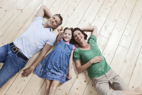 Eine glückliche Familie genießt die gemeinsame Zeit auf dem Boden liegend in München, Deutschland, lizenzfreies Stockfoto