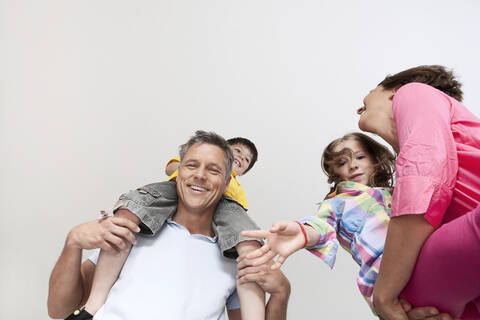 Glückliche Eltern in München, Deutschland, tragen freudig ihre lächelnden Kinder in einem herzerwärmenden Familienporträt, lizenzfreies Stockfoto