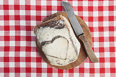 Herzförmiges Brot auf einem Holzbrett, bereit zum Schneiden mit einem Messer - GWF001641