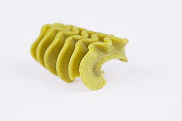 Close-up of green fusilli pasta on a white background, resembling accordions - GWF001644