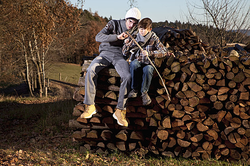 Ein Vater und sein Sohn genießen die freie Natur in Bayern, Deutschland, während sie gemeinsam Holz hacken - MAEF004011