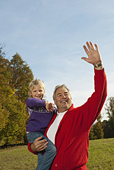 Glücklicher Familienmoment in Bayern: Ein stolzer Großvater trägt seine lächelnde Enkelin - RNF000783
