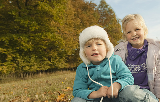 Fröhliche Mädchen genießen die bayerische Landschaft, sitzen im Gras und lächeln in die Kamera - RNF000804