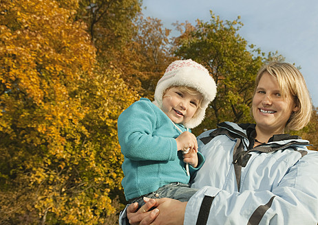 Eine fröhliche Mutter in Bayern trägt ihre lächelnde Tochter auf diesem herzerwärmenden Porträt - RNF000807