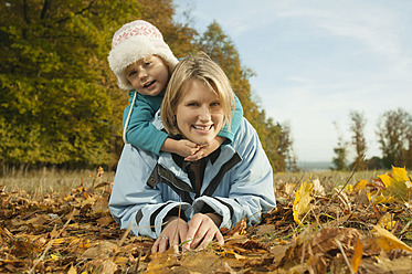 Eine glückliche Mutter und ihre Tochter genießen das Herbstlaub in Bayern, Deutschland, während sie für ein Porträt lächeln - RNF000810