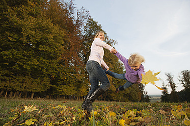 Eine Mutter und ihre Tochter genießen die Herbstzeit beim Spielen in Bayern, Deutschland - RNF000813