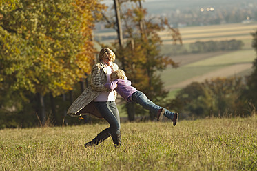 Eine Mutter und ihre Tochter genießen das Herbstwetter beim Spielen auf einer Wiese in Bayern, Deutschland - RNF000815