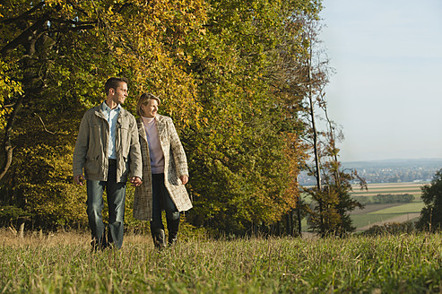 Ein Paar genießt die landschaftliche Schönheit Bayerns, Deutschland, bei einem gemütlichen Spaziergang durch das saftig grüne Gras - RNF000825