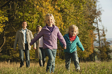 Eine Familie genießt einen malerischen Spaziergang durch eine schöne Wiese in Bayern, Deutschland, inmitten der leuchtenden Farben des Herbstes - RNF000831