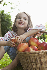 Germany, Bavaria, Munich, Girl sitting with basket of apples - RBF000786