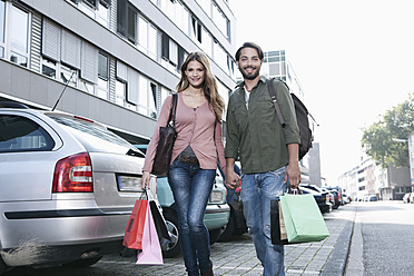 Deutschland, Köln, Junges Paar mit Einkaufstüten in der Nähe des Parkplatzes, lächelnd - FMKF000390