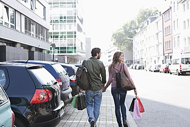 Deutschland, Köln, Junges Paar mit Einkaufstüten in der Nähe des Parkplatzes, lächelnd - FMKF000392
