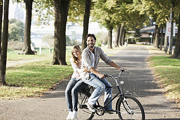 Deutschland, Köln, Junges Paar auf Fahrrad, lächelnd, Porträt - FMKF000402