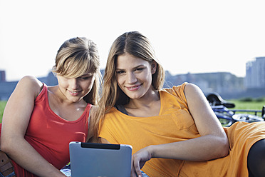 Germany, Cologne, Young woman using digital tablet, smiling - FMKF000405