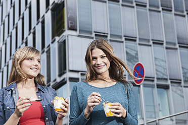 Germany, Cologne, Young woman with ice cream cup, smiling - FMKF000407