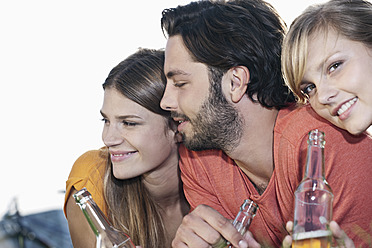 Germany, Cologne, Young man and woman lying in grass with beer bottles, smiling - FMKF000420