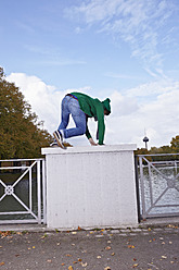 Germany, Cologne, Young man climbing on bridge railing - RHF000003