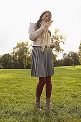 Deutschland, Köln, Junge Frau mit Handy im Park - RHF000008