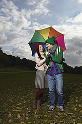 Deutschland, Köln, Junges Paar mit Regenschirm im Park, lächelnd - RHF000030