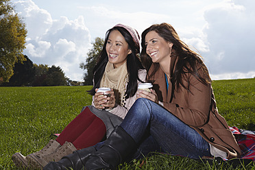 Deutschland, Köln, Frau mit Kaffee im Park, lächelnd - RHF000052