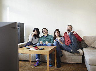 Germany, Cologne, Man and woman watching TV, smiling - RHF000091