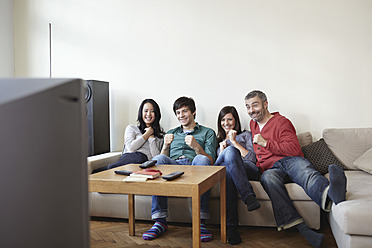 Germany, Cologne, Man and woman watching TV, smiling - RHF000092