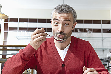 Germany, Cologne, Mature man holding spoon, portrait - RHF000098