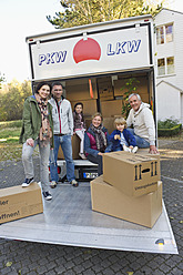 Germany, Bavaria, Grobenzell, Family with cardboard box in truck for moving house, smiling, portrait - WESTF018235