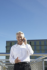 Germany, Bavaria, Munich,Businessman talking on phone, smiling, portrait - SKF000694