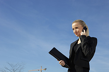 Deutschland, Bayern, München, Geschäftsfrau telefoniert mit Handy, lächelnd - SKF000719