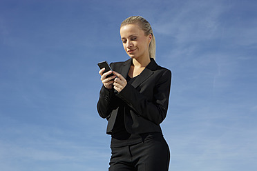 Deutschland, Bayern, München, Geschäftsfrau mit Mobiltelefon, lächelnd - SKF000720