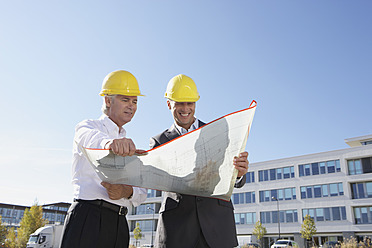 Germany, Bavaria, Munich, Engineers with blue print, smiling - SKF000735