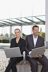 Deutschland, Bayern, München, Geschäftsleute mit Laptop, lächelnd - SKF000752