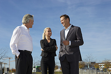 Deutschland, Bayern, München, Geschäftsleute stehen gegen den Himmel, lächelnd - SKF000757