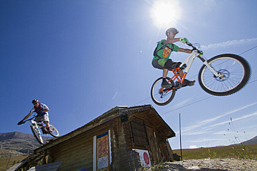 Frankreich, Dauphine, Vaujany, Mountainbiker springen von Hütte - FFF001245