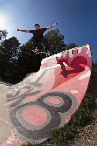 Germany, North Rhine-Westphalia, Ratingen, Skateboarder performing trick on ramp at skateboard park stock photo