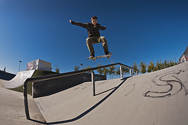 Germany, North Rhine-Westphalia, Duisburg, Skateboarder performing trick on ramp at skateboard park - KJF000156