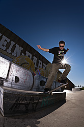 Germany, North Rhine-Westphalia, Duisburg, Skateboarder performing trick on ramp at skateboard park - KJF000157