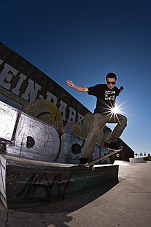Deutschland, Nordrhein-Westfalen, Duisburg, Skateboarder, der einen Trick auf einer Rampe im Skateboard-Park vorführt - KJF000157